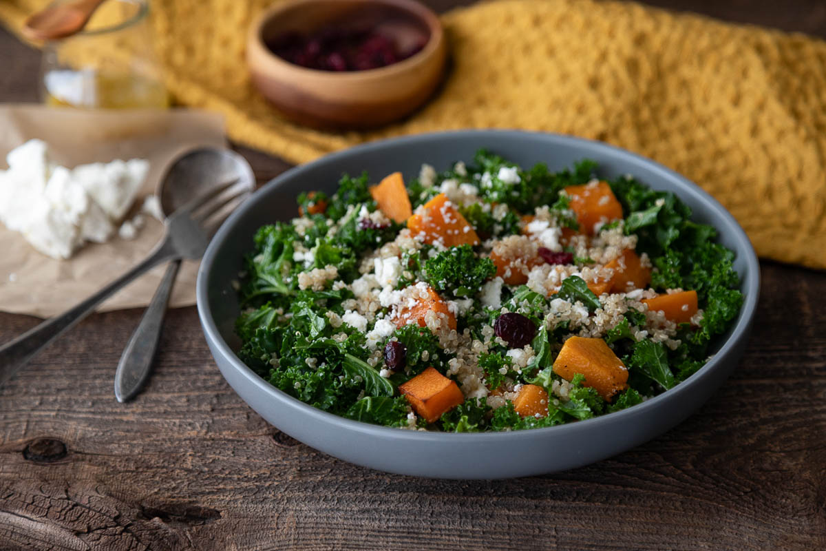 quinoa butternut squash salad in bowl with golden yellow napkin